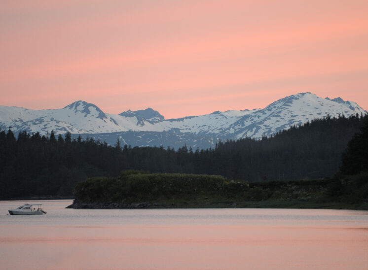 Near midnight in Juneau, in an everlasting sunset awash with pink. Mountains and a solitary boat framed by the glowing sky. Jerry and Lois Photography