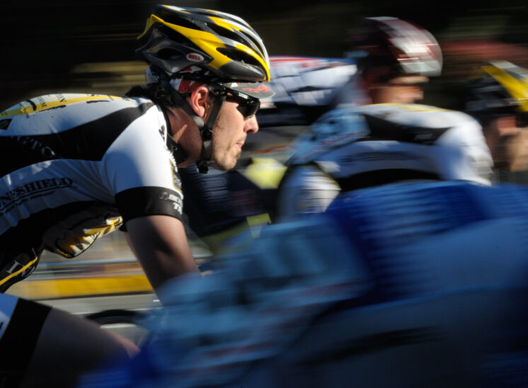 Redmond Derby Days. A pack of racing cyclists flash past with stretched out motion blur. One cyclist remains in tack-sharp focus as the sun paints him in light. © Jerry and Lois Photography, all rights reserved